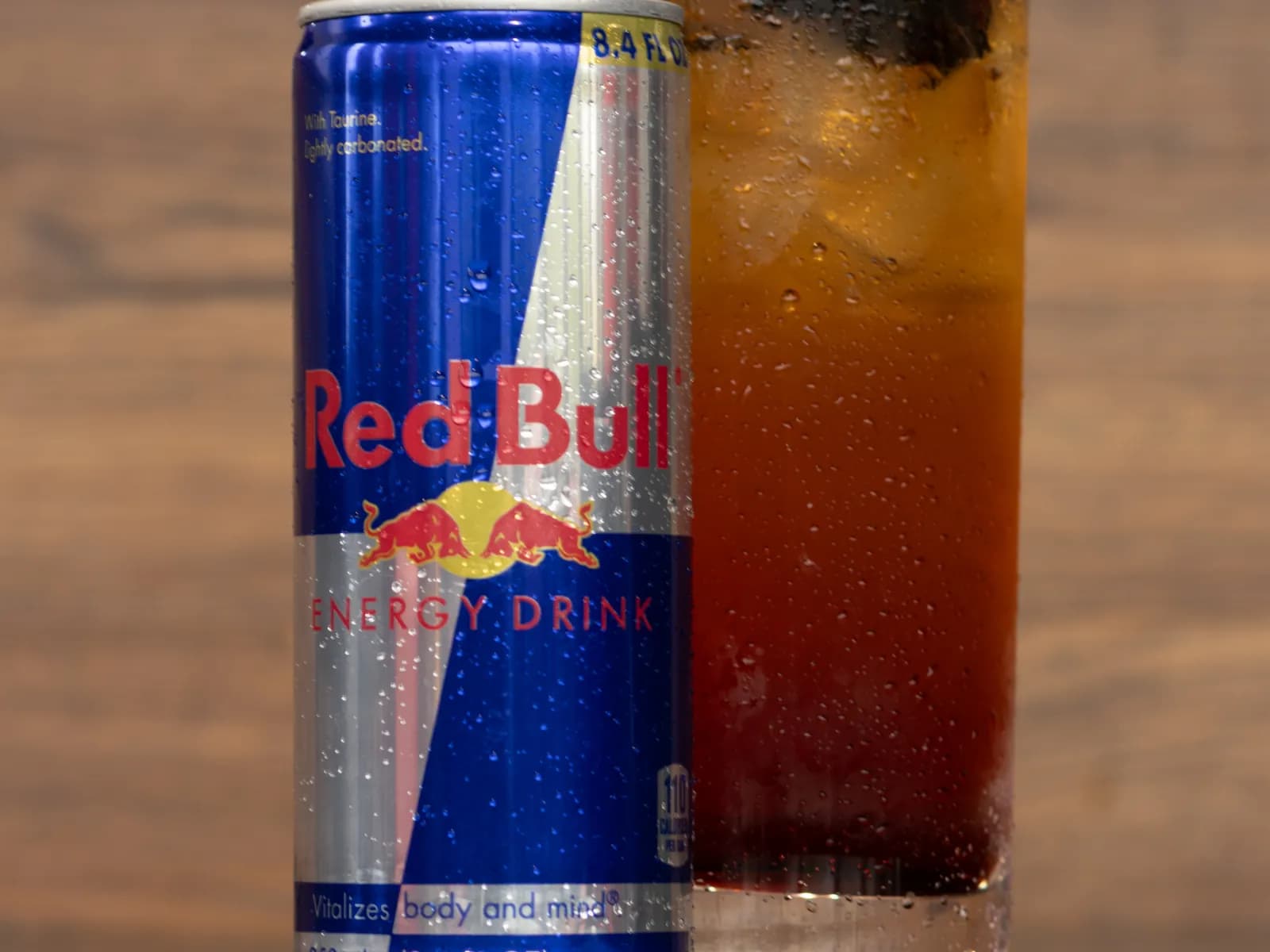 A can of Red Bull Energy Drink beside a tall Blackberry Bramble Infusion over ice