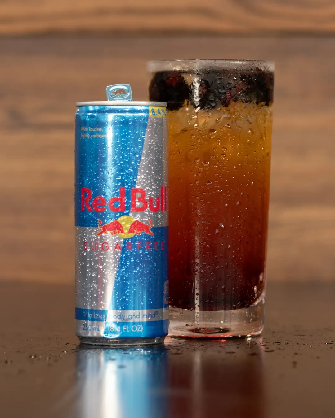 A can of Red Bull Sugarfree beside a tall Blackberry Bramble Infusion over ice