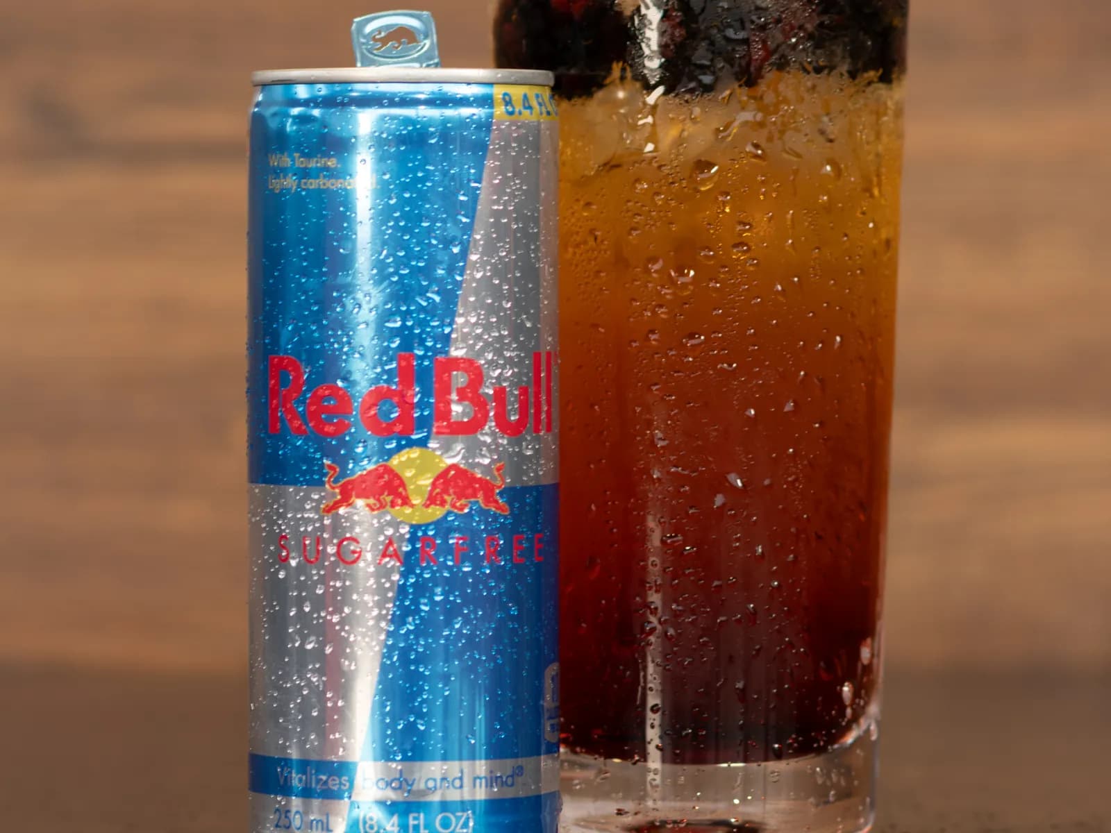 A can of Red Bull Sugarfree beside a tall Blackberry Bramble Infusion over ice